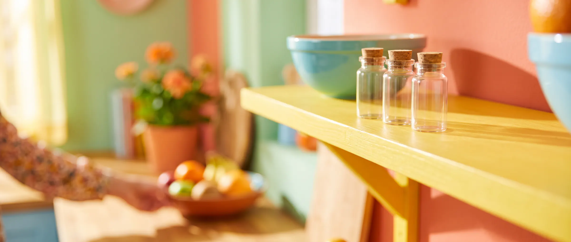 Three small corked glass vials on a sunny yellow shelf