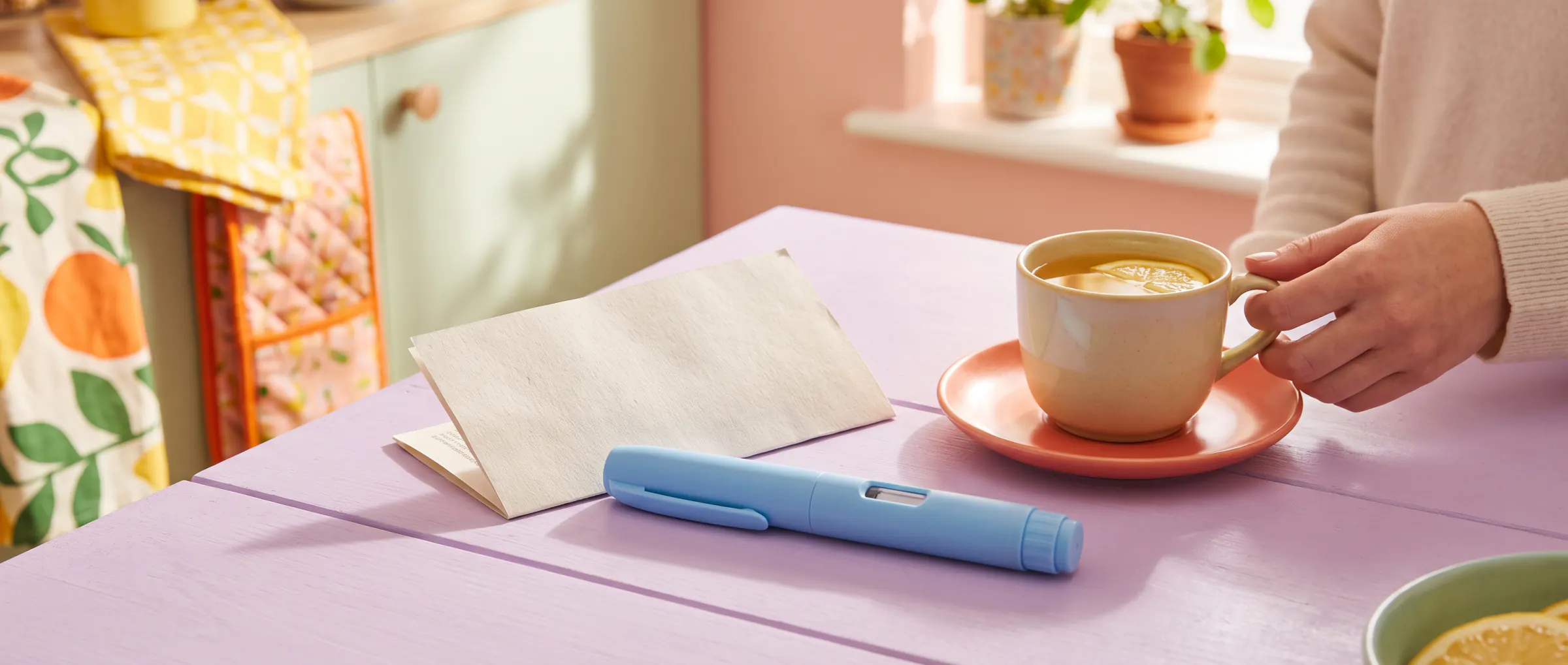 An injection pen beside a folded leaflet on a sunny lilac table